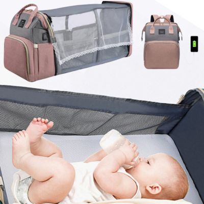 Baby lying on a crib with a diaper bag and backpack in the background